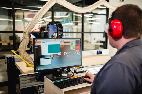 operator wearing haring protecting uses a computer to control a manufacturing process